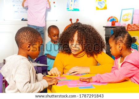 Little black girl and boy in the nursery school learn cursive letters by tactile cards with teacher