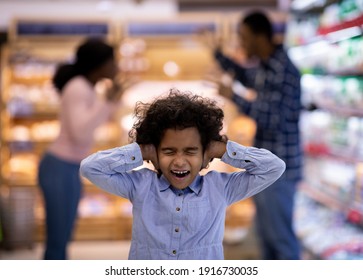 Little Black Girl Covering Her Ears And Shouting While Her Parents Arguing At Supermarket. Desperate African American Child Cannot Stand Her Mom And Dad's Conflict At Shopping Mall