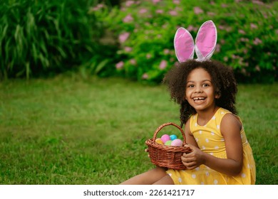 Little Black girl wtfring bunny ears gathering Easter eggs - Powered by Shutterstock