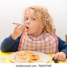 A Little Blond Boy Eating Pasta With Tomato Sauce