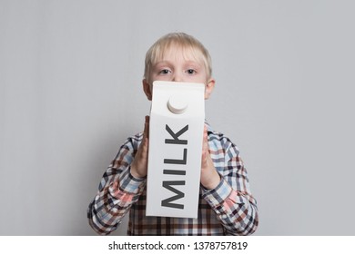 Little Blond Boy Is Holding A Big White Carton Milk Package. Light Background