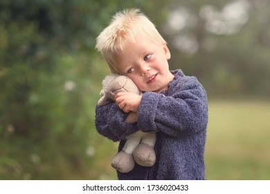 Little blond boy holding plush sheep in the park - Powered by Shutterstock