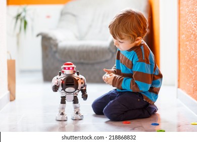 Little blond boy playing with robot toy at home, indoor