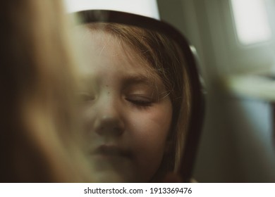 Little Blond Girl With Blue Eyes Looking In The Mirror. Cute Serious Curious Child Admires Herself In Reflection. Kids Home Portrait In Daylight Near Window. Growing Up Psychology Personal Development