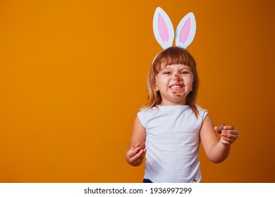 Little Blond Girl With Dirty Chocolate Bunny Ears Eating Easter Egg