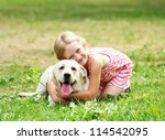 A little blond girl with her pet dog outdooors in park