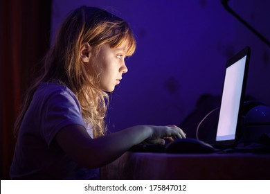 Little Blond Girl Working On Laptop In Dark Room At Night