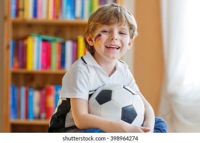 Little Blond Preschool Kid Boy With Ball Watching Soccer European Cup Game On Tv. Funny Child Fan Having Fun And Cheering Winning Football Team. Champions League Concept.