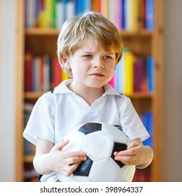 Little Blond Preschool Kid Boy With Ball Watching Soccer European Cup Game On Tv. Sad Crying Child About Lost Game Of His Football Team. Champions League Concept.