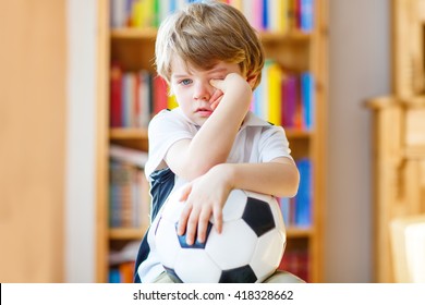 Little Blond Preschool Kid Boy With Ball Watching Soccer European Cup Game On Tv. Sad Crying Child About Lost Game Of His Football Team. Champions League Concept.