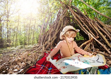 Little blond scout boy sit with treasury map playing treasure hunt game over hut of branches - Shutterstock ID 2170313935