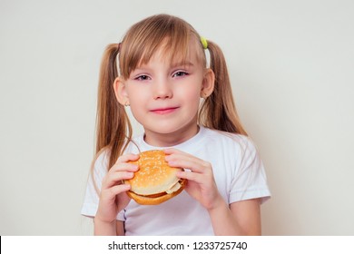 Little Blonde Girl Is Eating Baked Vegetarian Burger With Vegetables. Child Vegan Idea Healthy Eating Concept