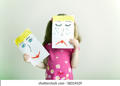 Little Blonde Girl Holding Happy And Sad Face Masks Symbolizing Changing Emotions