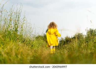 a little blonde girl runs around in a yellow raincoat in nature after the rain, rear view, happy childhood. - Powered by Shutterstock