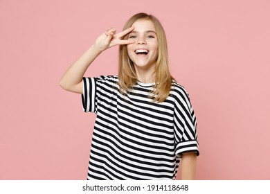 Little blonde smiling kid girl 12-13 years old wearing striped oversized t-shirt cover eye with victory v-sign gesture isolated on pastel pink background children studio. Childhood lifestyle concept - Powered by Shutterstock