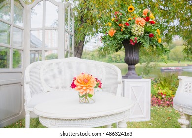 A little bouquet stands on the white table before a white garden couch - Powered by Shutterstock