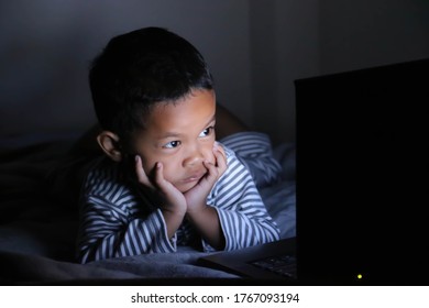 The Little Boy Addicted To Computer. At Night In The Dark.