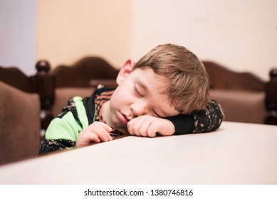 A Little Boy After A Walk In The Fresh Air Is Very Tired And Fell Asleep In The Kitchen On The Table, Do Not Wait Until Mom Will Give It To Eat. A Boy Is Sweetly Sleeping