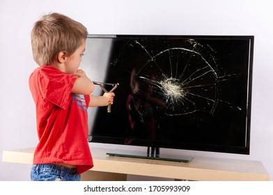 Little Boy Aiming To A Cracked TV Screen With A Slingshot. 