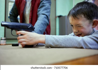 Little Boy Aims Pistol In Shooting Gallery.