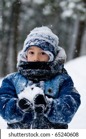 little boy  all bundled up in a snowsuit holding a snowball