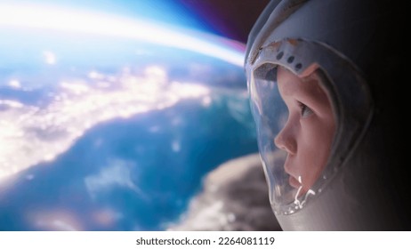 Little boy with an astronaut helmet looks at earth and sunrise in space from spaceship. Children's dreams of conquering space. - Powered by Shutterstock