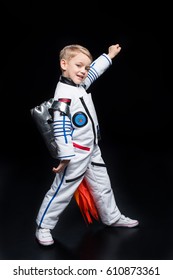 Little boy astronaut in space suit playing and smiling at camera  isolated on black