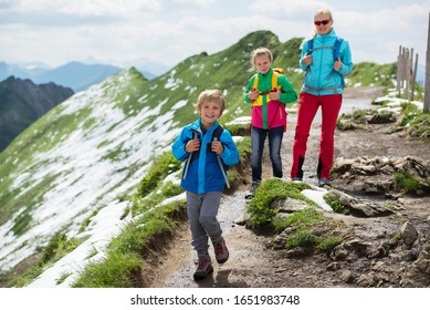 Little boy with backpack hiking in the mountains. 
Happy family during summer vacation in the mountains.