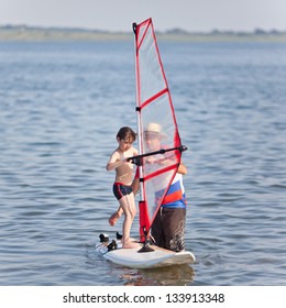 Little Boy Begins Learning Windsurfing And Gets A Lesson From A Male Instructor