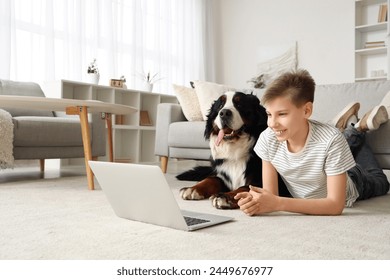 Little boy with Bernese mountain dog watching cartoons on laptop at home - Powered by Shutterstock