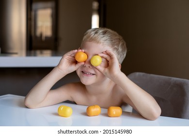 A little boy blonde plays with yellow capsules from kinder surprise, smiles, he is happy
