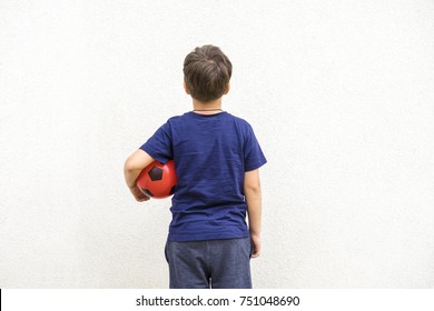 Little boy in blue shirt holding red ball, back view. Copyspace for text