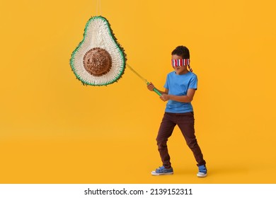Little boy breaking Mexican pinata on color background - Powered by Shutterstock