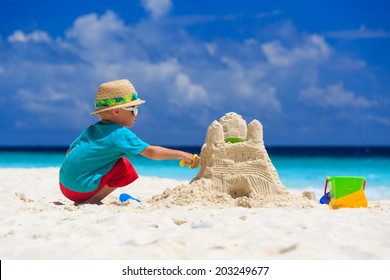 little boy building sand castle on tropical beach