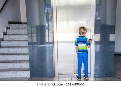 Little boy is calling the elevator next to staircase