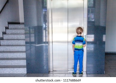 Little boy is calling the elevator next to staircase