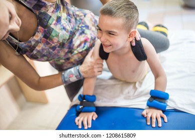 Little Boy With Cerebral Palsy Has Musculoskeletal Therapy By Doing Exercises. Child And Therapist