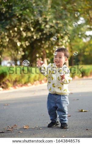 A little boy chasing bubbles and playing