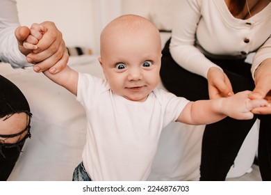 Little boy child baby playing with parents, standing learning to walk, taking first steps. Playful toddler with bulging big eyes having fun, making faces grimaces. Happy childhood, family concept
 - Powered by Shutterstock