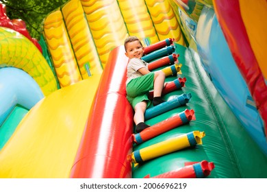 Little boy child climbs the stairs of a multi-colored slide in the park. - Shutterstock ID 2006696219