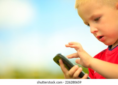 Little Boy Child Kid  Playing Games On Smartphone Mobile Phone Outdoor. Technology Generation.