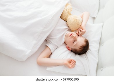 Little Boy Child Waking Up At The Morning. Hugging His Favourite Teddy Bear