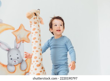 A Little Boy In A Children's Playroom With A Wigwam And A Giraffe Playing With Wooden Toys With Cubes, Child Development. Baby Rides A Giraffe Toy