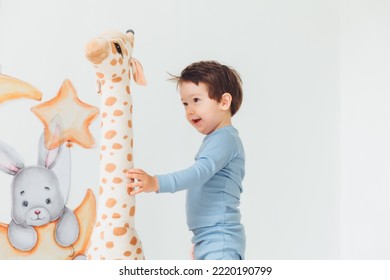 A Little Boy In A Children's Playroom With A Wigwam And A Giraffe Playing With Wooden Toys With Cubes, Child Development. Baby Rides A Giraffe Toy