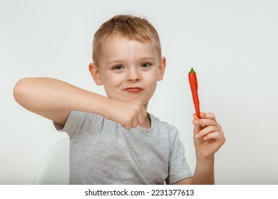 Little boy with chili pepper on white background. Extra hot cayenne pepper. Boy holding spicy red chili pepper. Portrait of a shocked child. Hot.