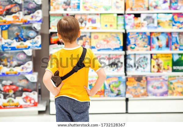 Little boy choosing\
toys for birthday gift. Many toys around. Kids shop. Sales,\
discounts and shopping. Cute boy selecting toys in store. Child\
doing shopping in toys\
shop.
