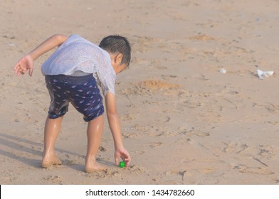 Little Boy Is Cleaning Up Garbage On The Beach For Enviromental Clean Up Concept