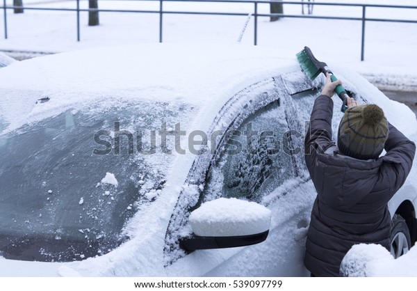 little boy cleans snow from\
car