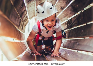 Little boy climbing in adventure activity park with helmet and safety equipment - Powered by Shutterstock