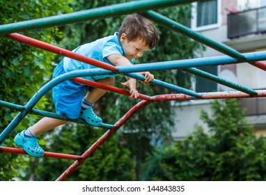 Little boy climbing on jungle gym without rope and helmet on playground, dangerous - Powered by Shutterstock